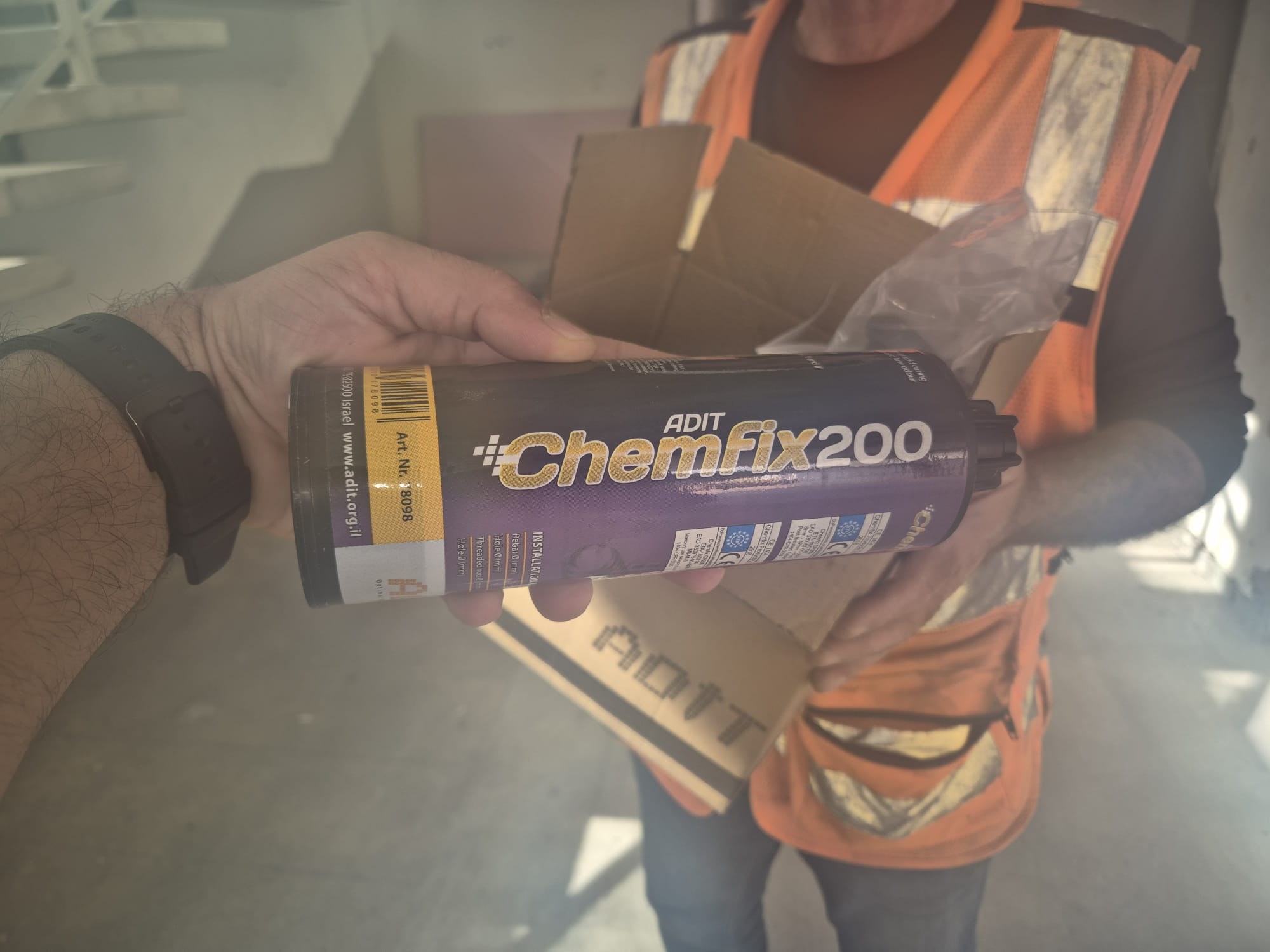 איש מחלקת בטיחות מחלק מוצר Chemfix 200 לעובד באתר בנייה.