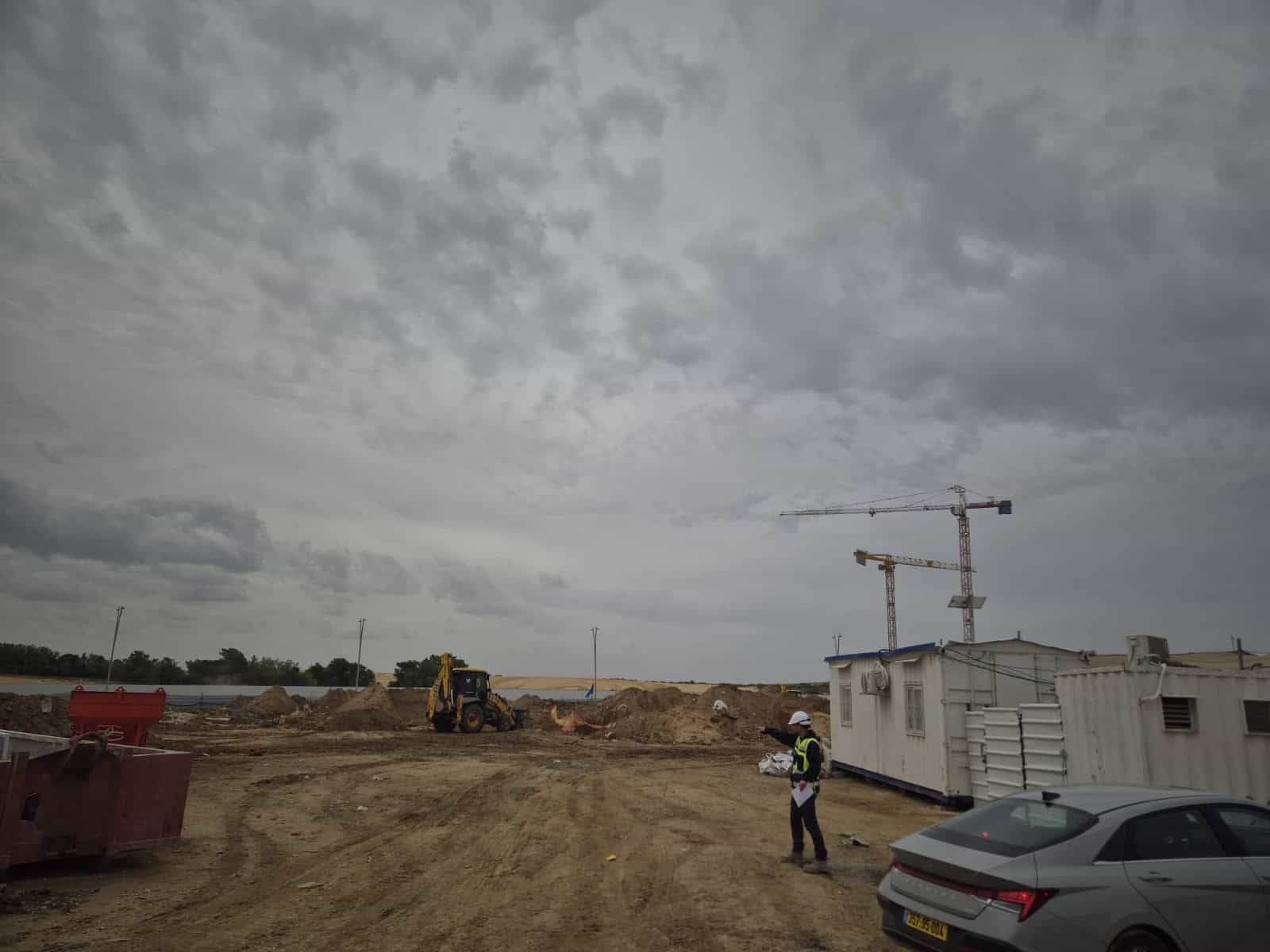 אתר בנייה עם מכשיר עבודה וגנרטור תחת שמיים מעוננים.