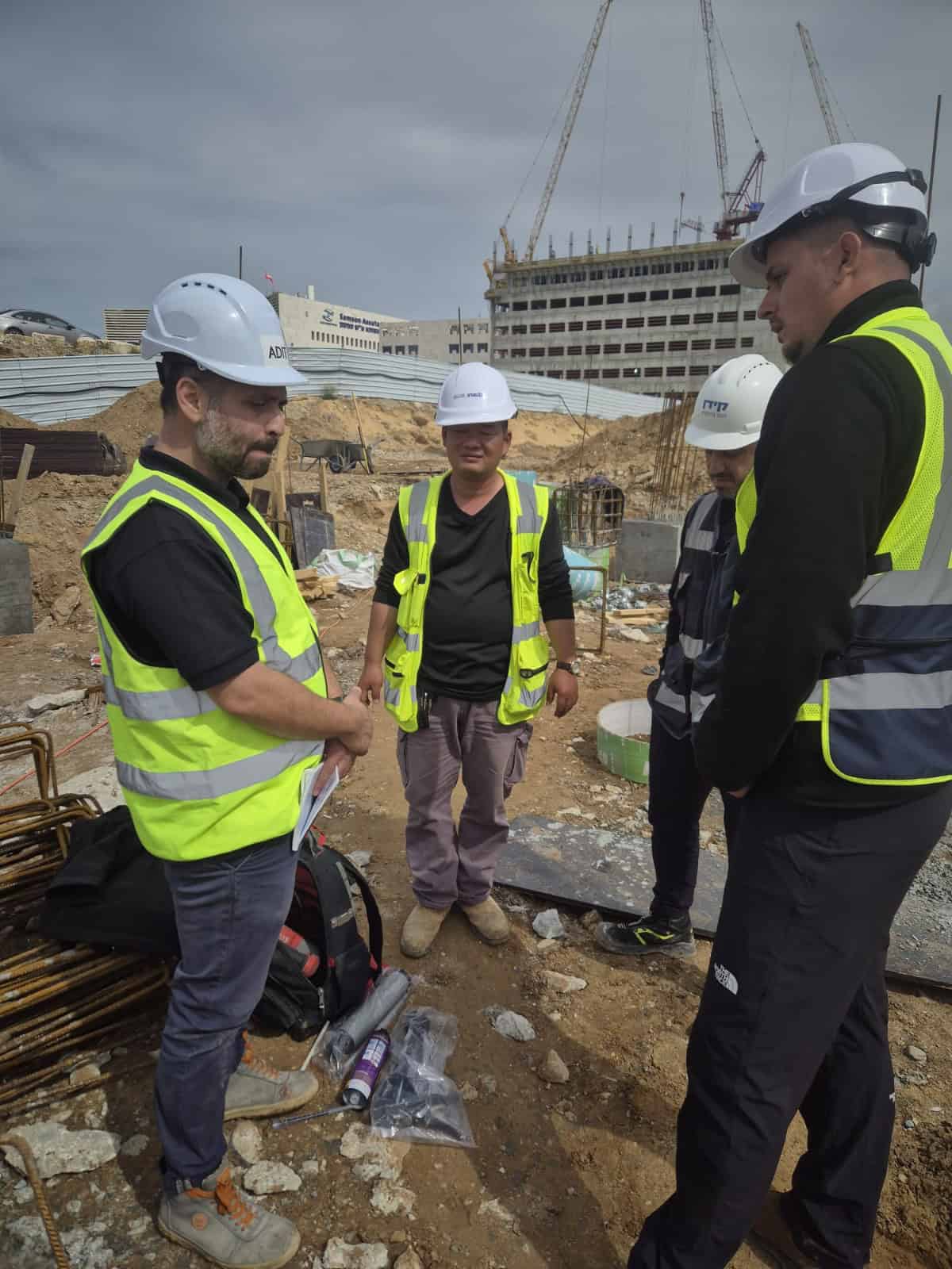 קבוצת מהנדסים באתר בנייה עם קסדות ווסט בטיחות.