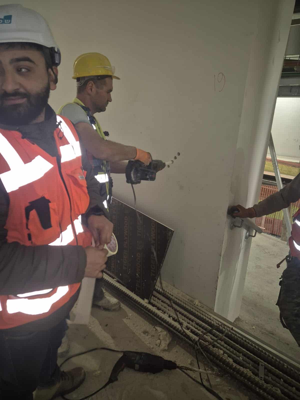 עובדי חשמל באתר בנייה עם ציוד מגן, מתקינים תשתיות חשמל.