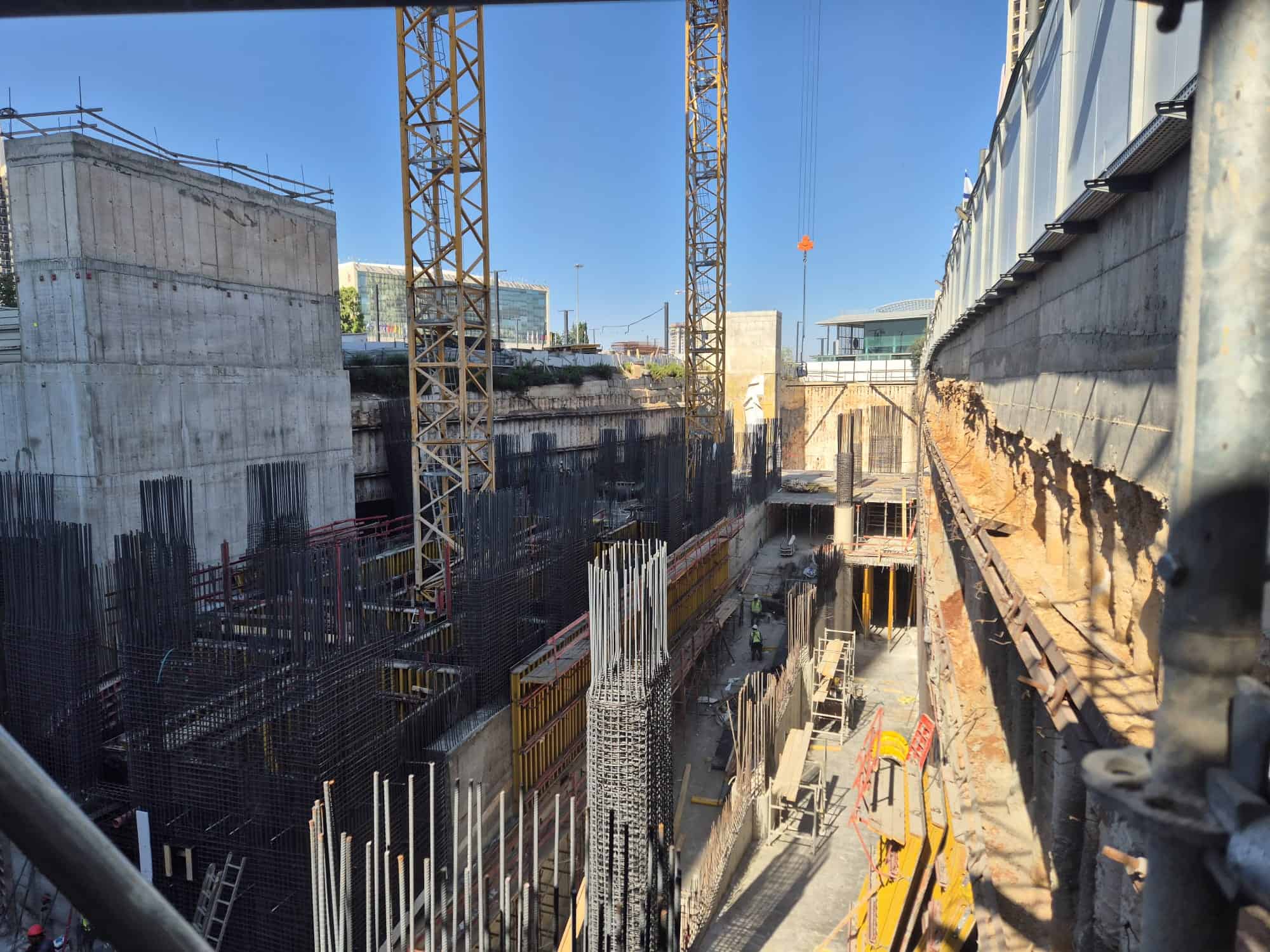 אתר בנייה פעיל עם מנופים ועובדים, מוכן לבנייה עתידית.